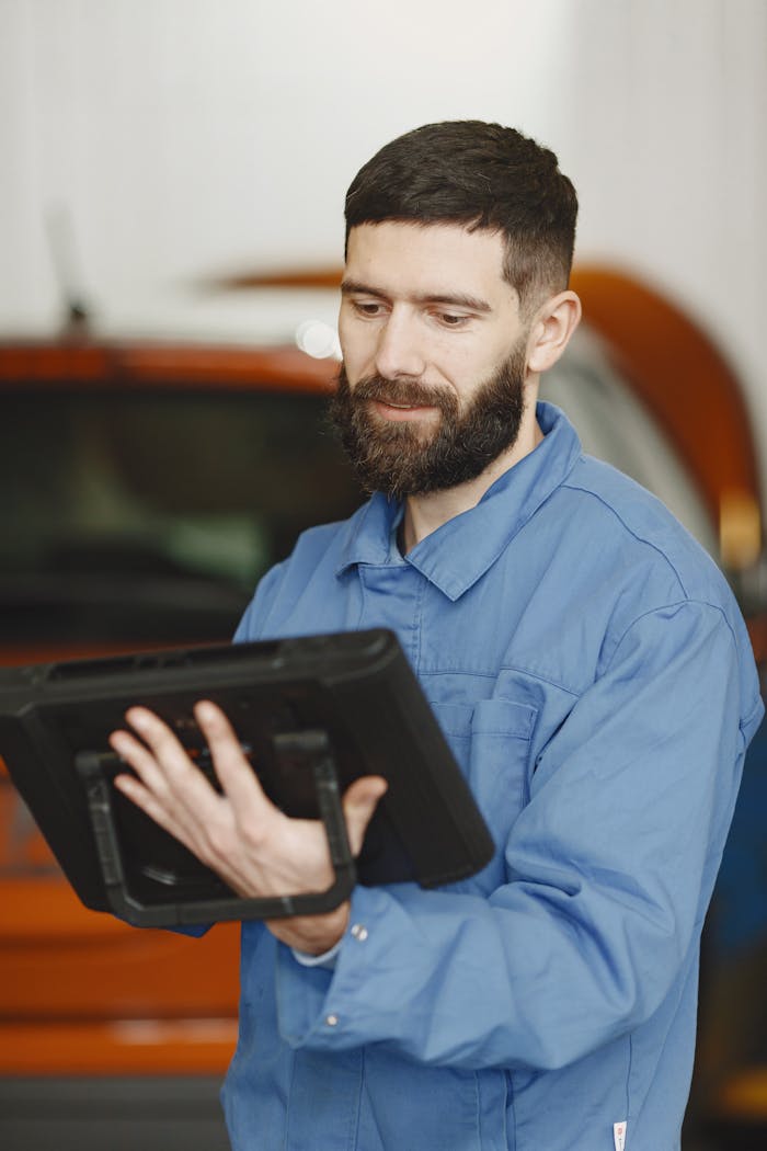 Home Bearded male mechanic using a tablet for diagnostics in a workshop setting.