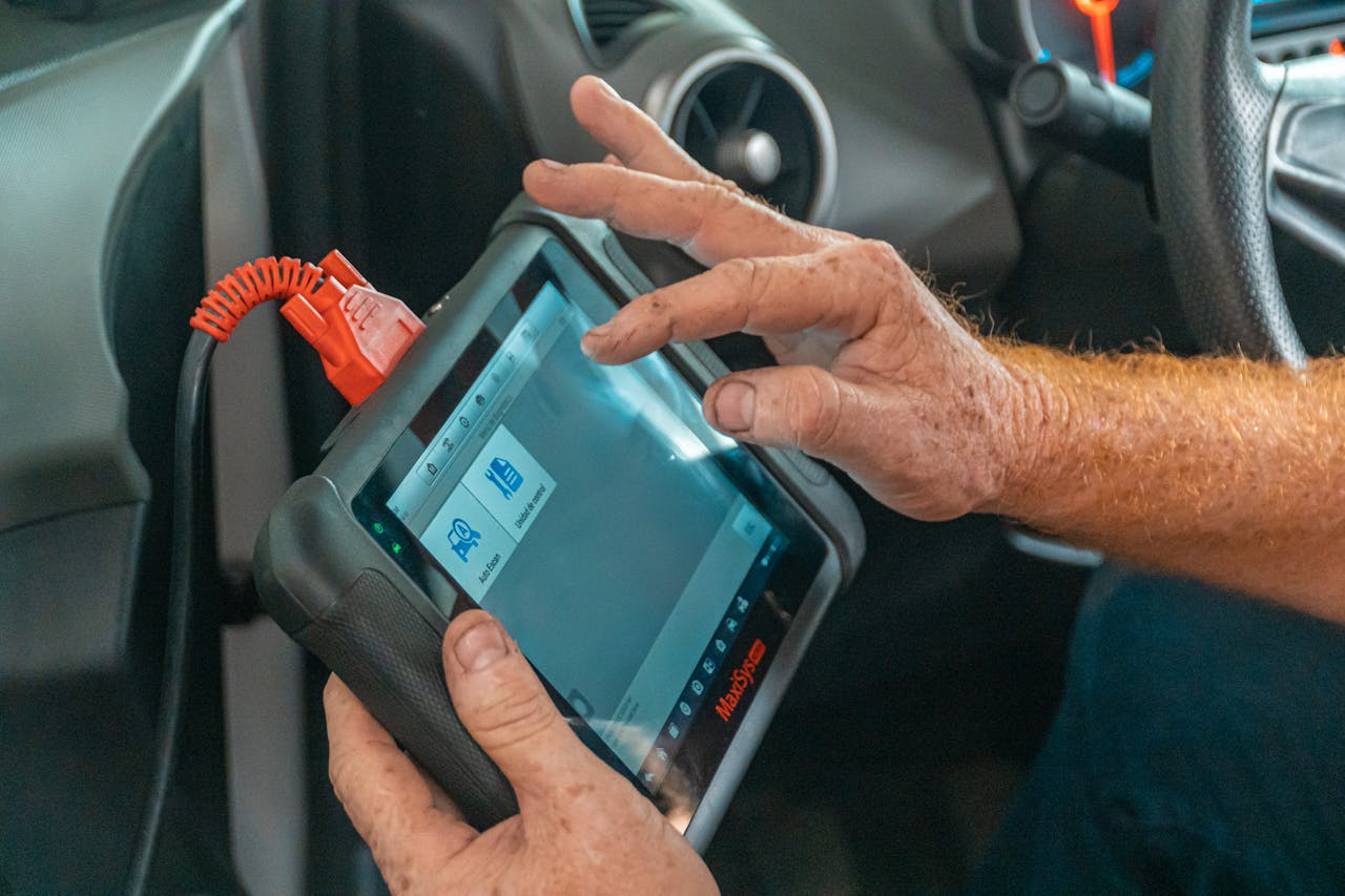 Home Mechanic using a diagnostic tool inside a car to check for engine issues and ensure proper maintenance.