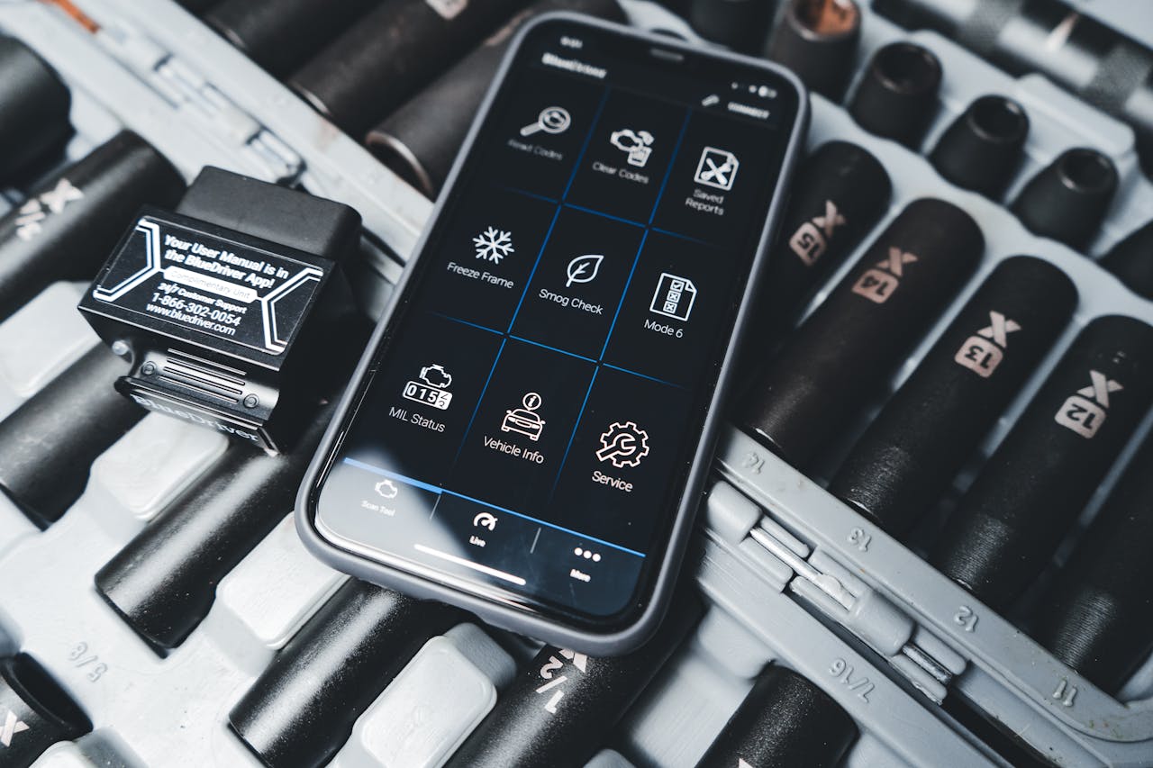 Home Close-up of a smartphone showing car diagnostic app with OBD2 scanner in a garage setting.